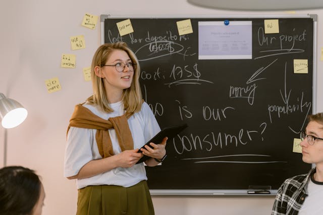 Photo by Tima Miroshnichenko: https://www.pexels.com/photo/a-woman-in-white-shirt-standing-near-the-chalkboard-6914632/